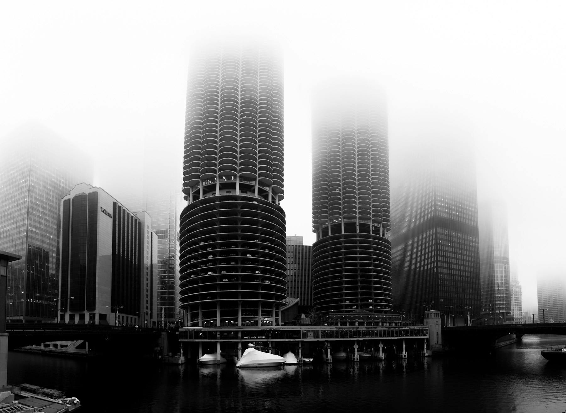 a black and white shot of the two towers of Marina city enveloped in fog.